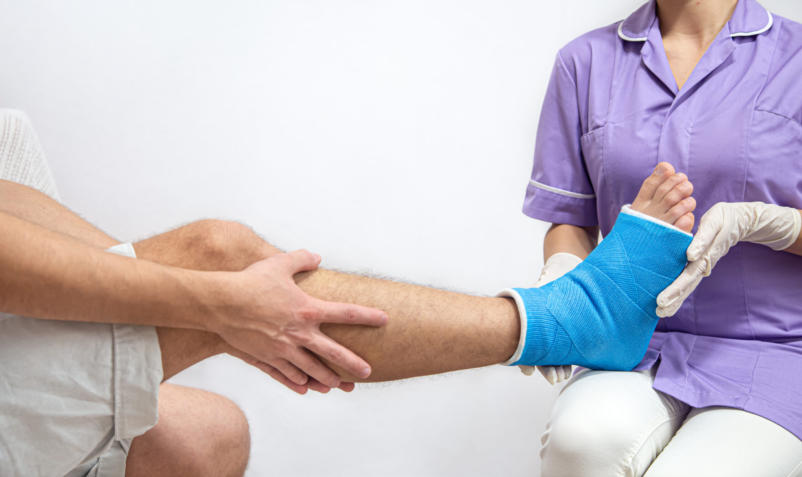 Close up of a man's leg in a cast and a blue splint after bandaging in a hospital.